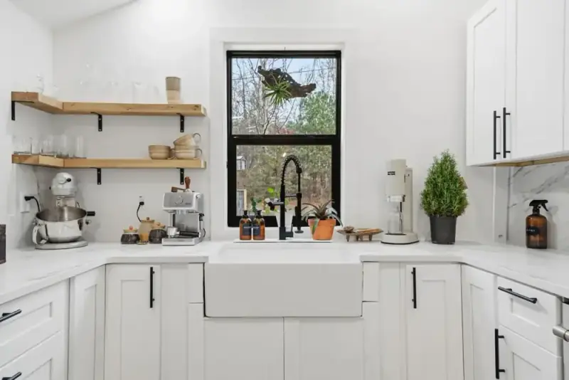 White kitchen sink area at 356 Hyde Road with open shelving, appliances, and a wooded window view