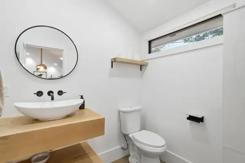 Small bathroom at 356 Hyde Road with a vessel sink, toilet, wall mirror, and white walls