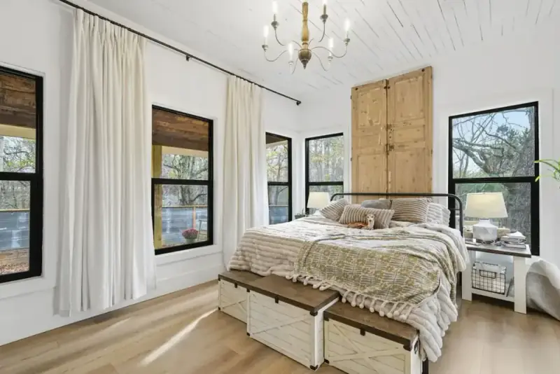 Bedroom at 356 Hyde Road with a bed, chandelier, wood-look floors, and windows overlooking trees