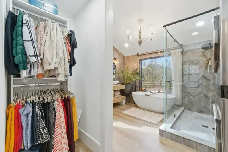 Open clothing closet beside a bathroom at 356 Hyde Road with hanging storage and a glass shower