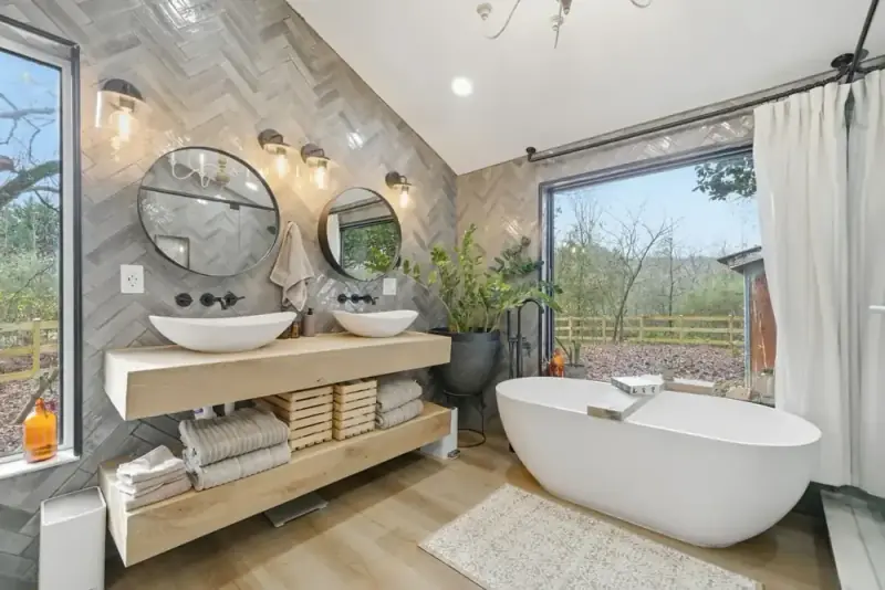 Primary bathroom at 356 Hyde Road with freestanding tubs, a glass shower, and forest views