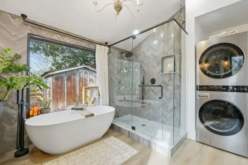 Bathroom at 356 Hyde Road with a freestanding tub, glass shower, double vanity, and wooded view