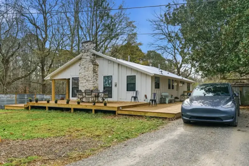 Front exterior of 356 Hyde Road with a covered porch, stone chimney, lawn, and gravel drive