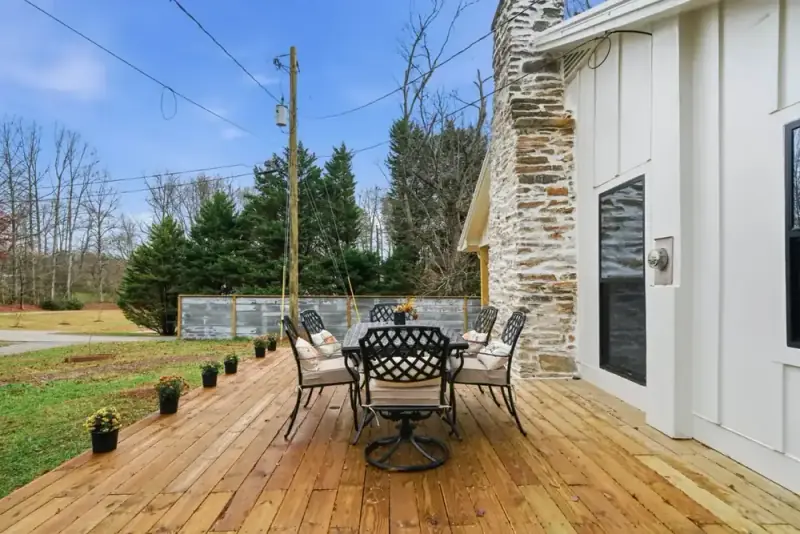 Outdoor deck at 356 Hyde Road with a patio table, potted plants, and wooded surroundings