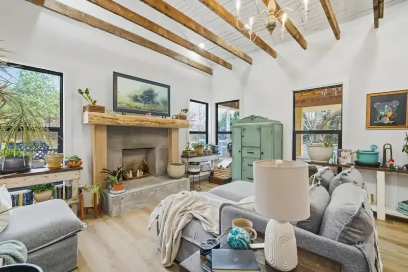 Open living room at 356 Hyde Road with a stone fireplace, sofas, exposed beams, and windows