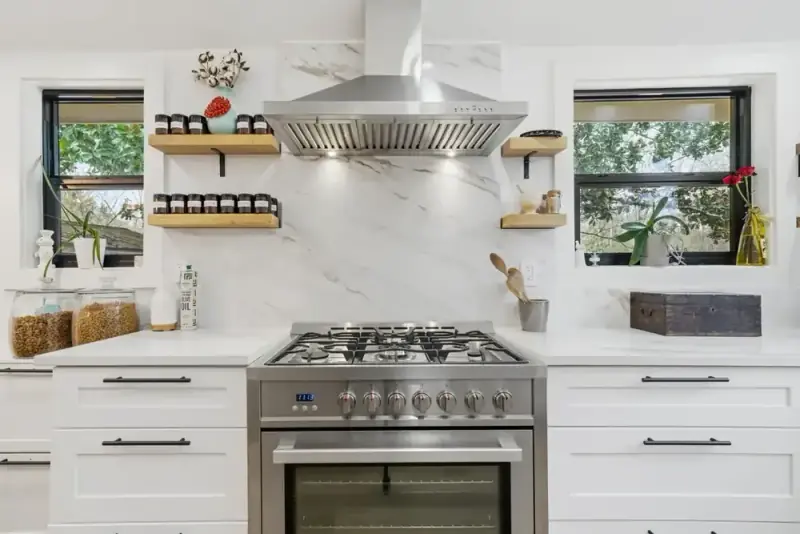 Kitchen range and prep area at 356 Hyde Road with white cabinets, open shelves, and a window