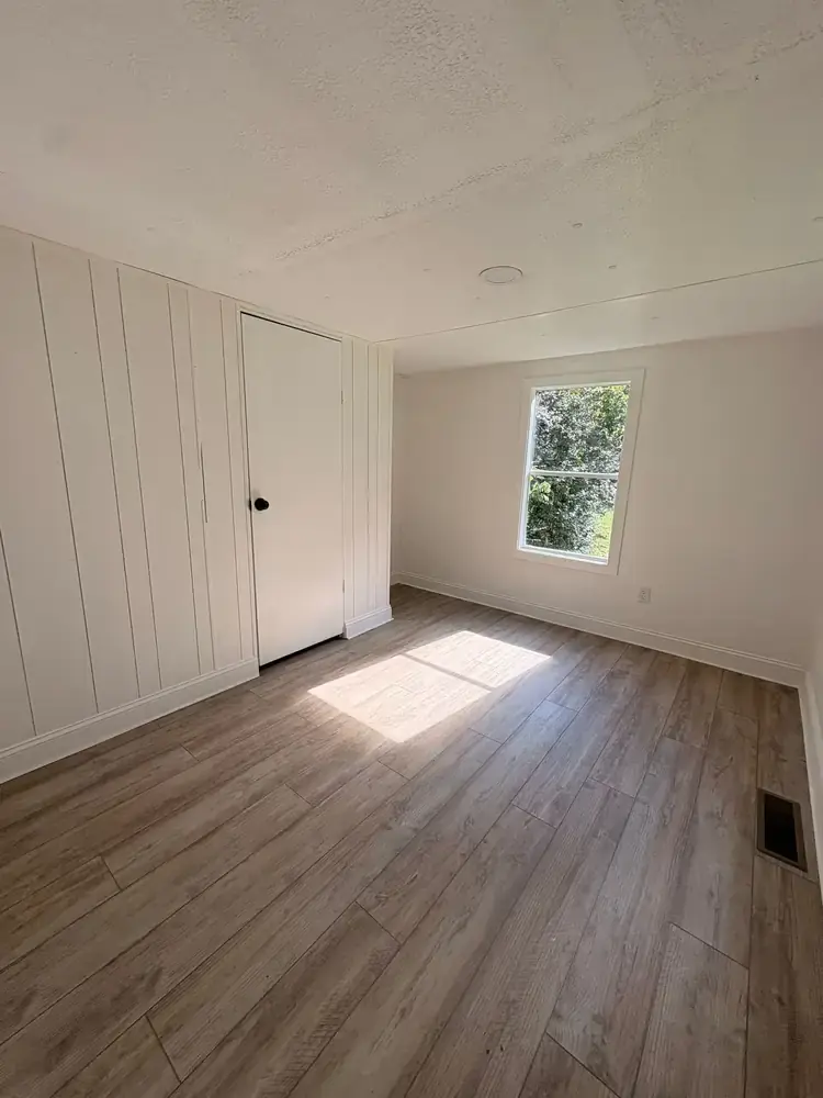 Sunlit bedroom with paneled walls, wood-look flooring, and a built-in closet at 495 Pack Road in Ranger