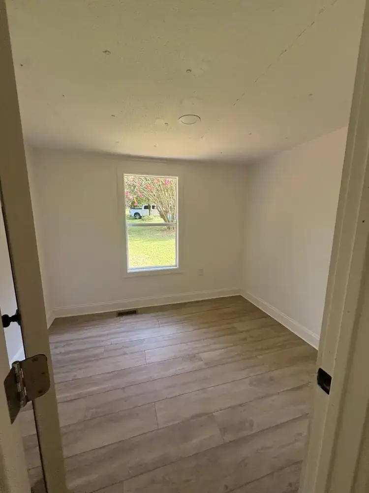 Second bedroom with wood-look flooring and a bright backyard view at 495 Pack Road in Ranger