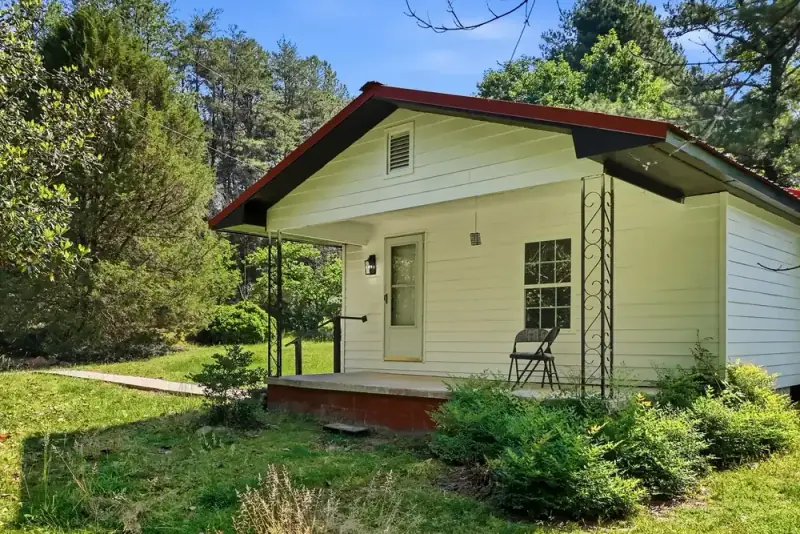 Single-story white home and wooded yard at 497 Pack Road in Ranger